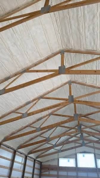 Spray foam between the roof trusses of a framed building.